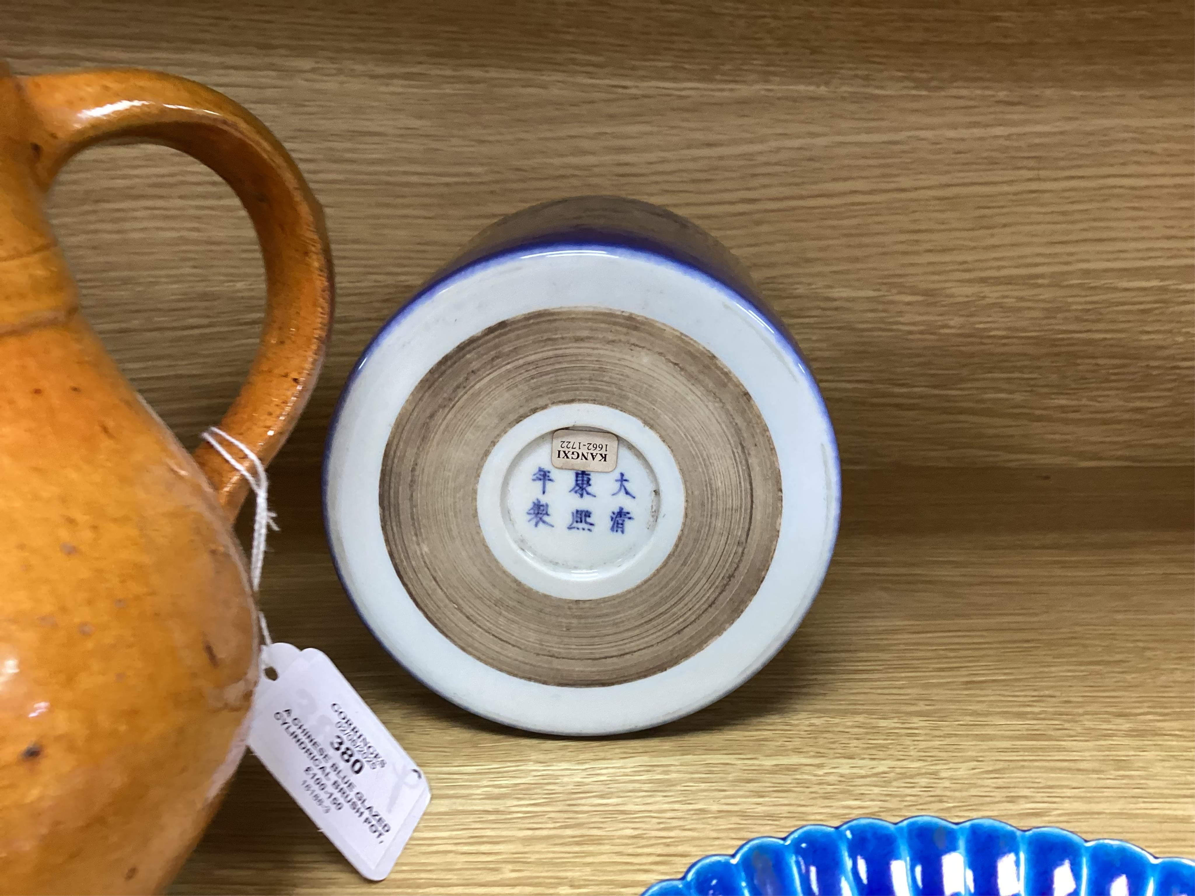 A Chinese blue glazed cylindrical brush pot, Kangxi mark but later, a similar saucer, Qianlong mark but later and a terracotta jug, 21cm